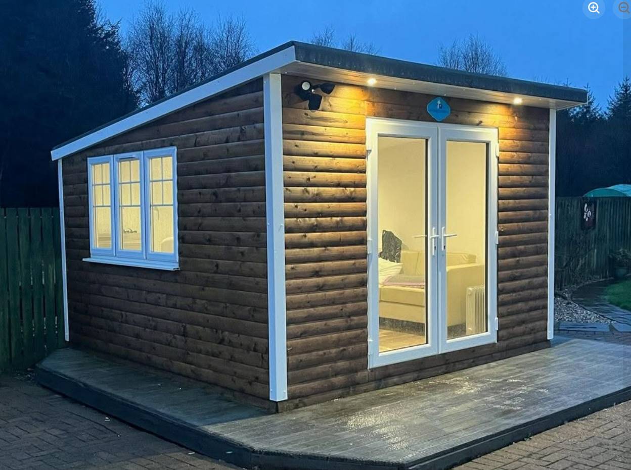 OD Garden Rooms timber-clad garden room with French doors lit up in the evening